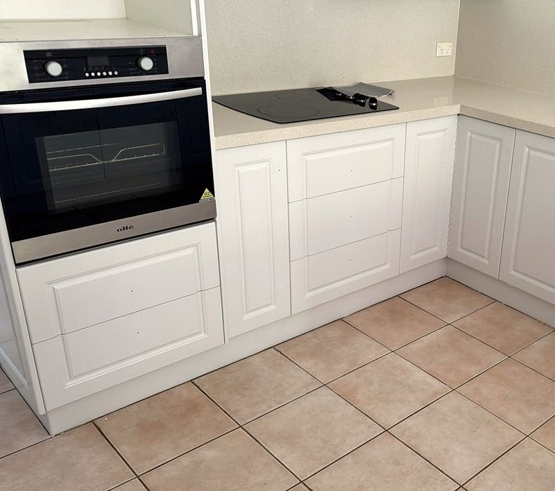 Wide view of an L-shaped kitchen with white-painted cabinetry