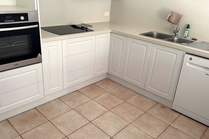 Wide view of an L-shaped kitchen with white-painted cabinetry