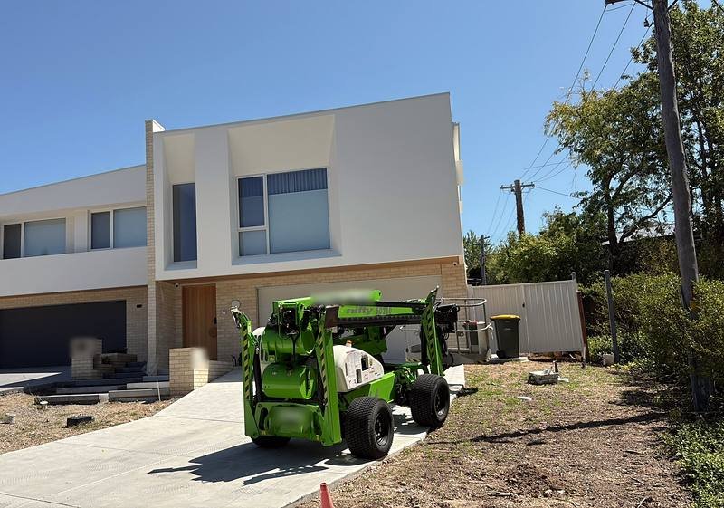 Boom lift parked in front of a two-storey new build during exterior work