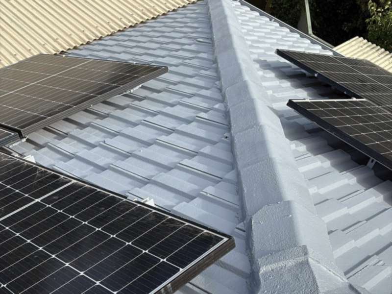 Tiled roof freshly coated in light grey, with solar panels along the ridge