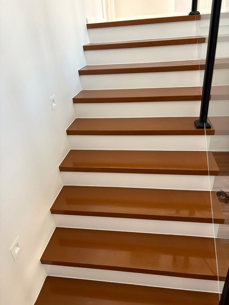 Staircase with gloss-finished timber treads, crisp white risers and a black handrail
