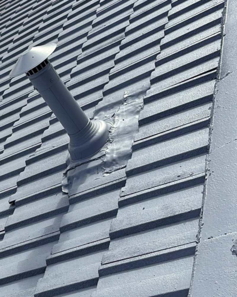 Coated roof tiles around a coated flue and its resealed flashing