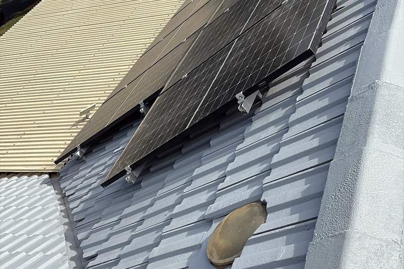 Coated roof valley running between rows of solar panels