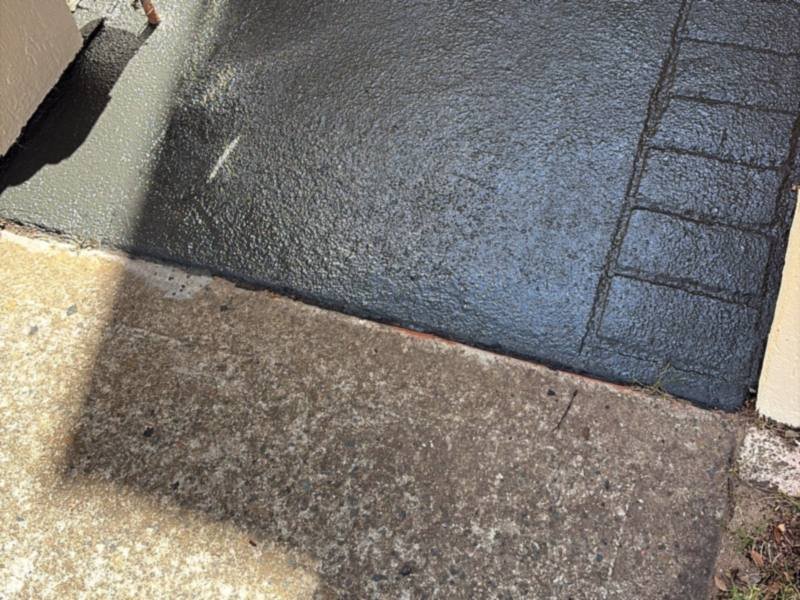 A front path where the fresh charcoal coating meets the original, untreated concrete