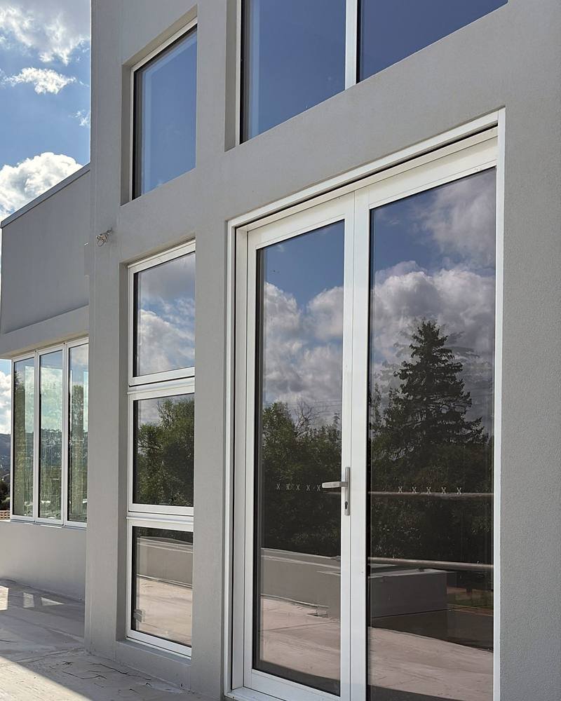 Two-storey extension with a smooth grey rendered finish and full-height glazing
